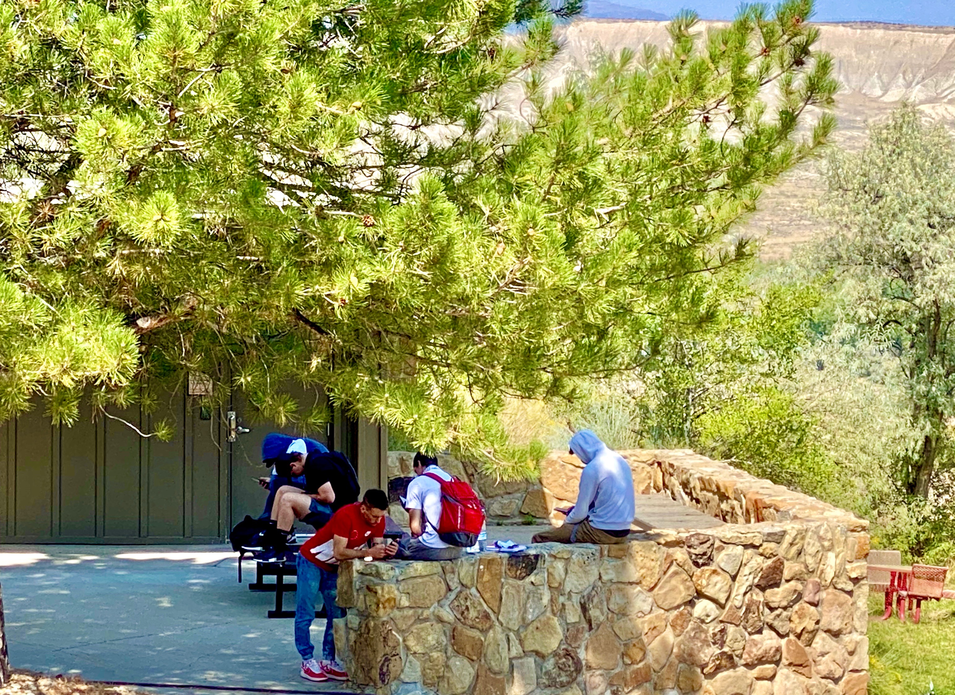 Students on Campus Hanging Out on Rock Wall with Book Cliff Mesas in Background