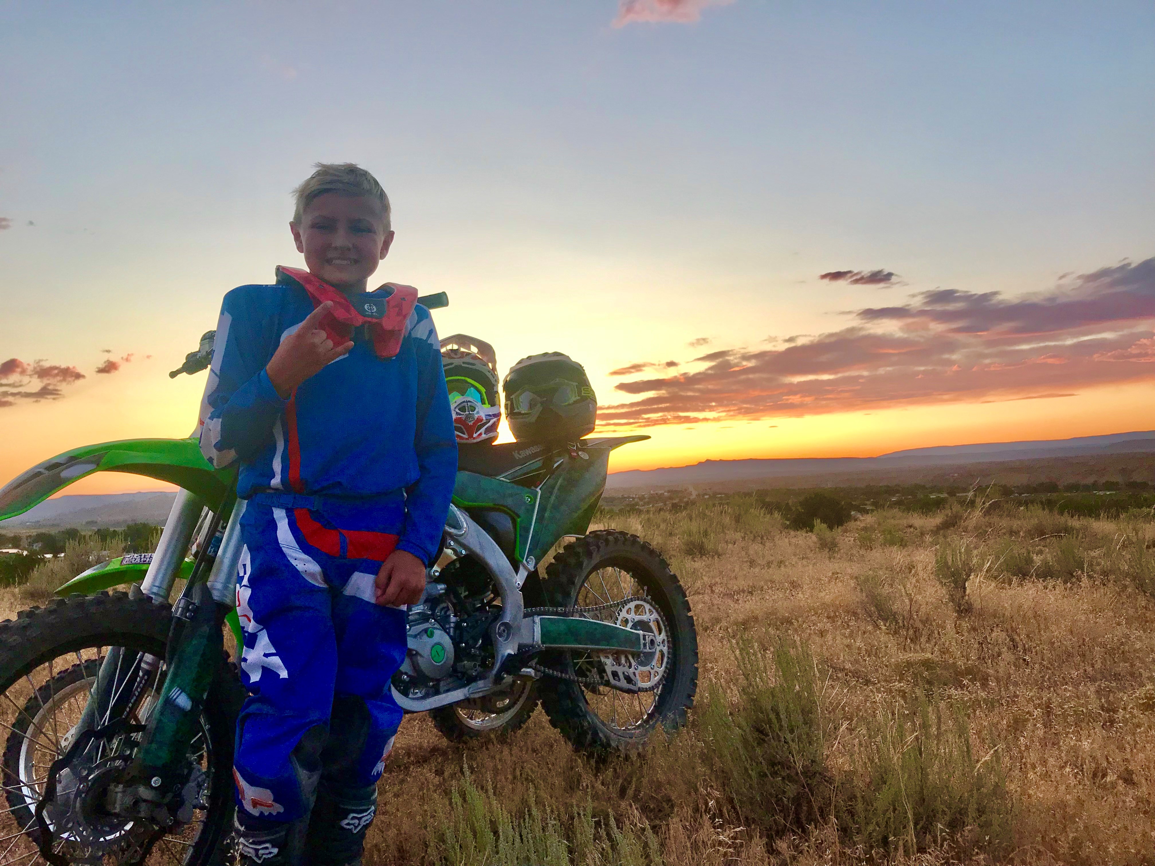 A Young Man at Sunset beside a dirt bike