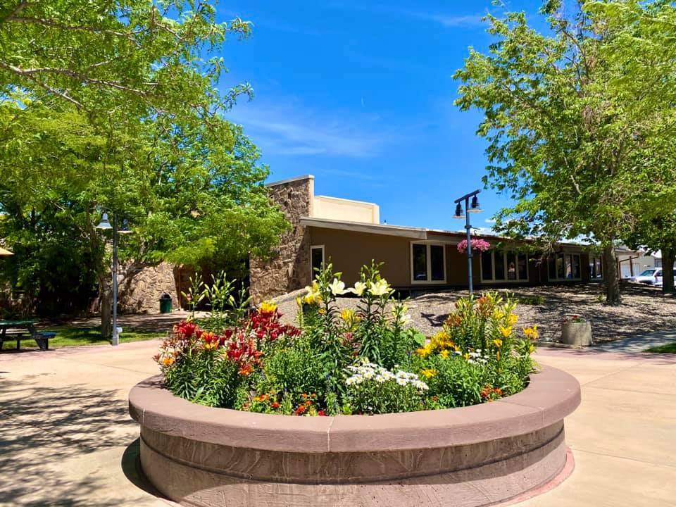 Round flower bed full of colorful flowers in forefront with Town Hall building located behind it